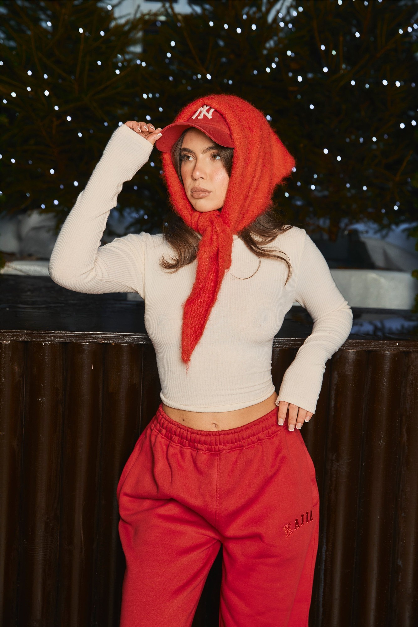 Ivory ribbed long sleeve top with a roll neck, featuring fitted sleeves and a cropped design, paired with red sweatpants and a red cap.