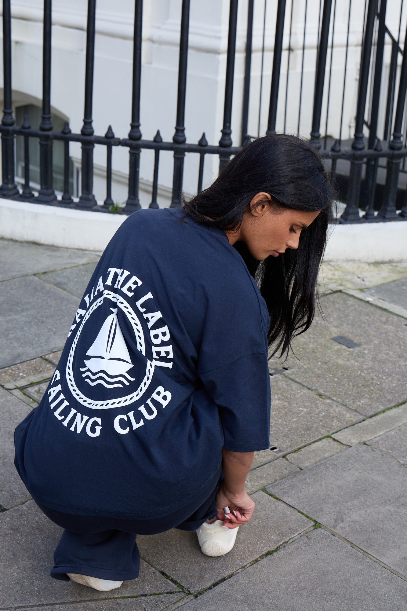 Oversized ink blue t-shirt featuring a white sailing club graphic on the back, made from soft material, styled with a relaxed fit and dropped shoulders.