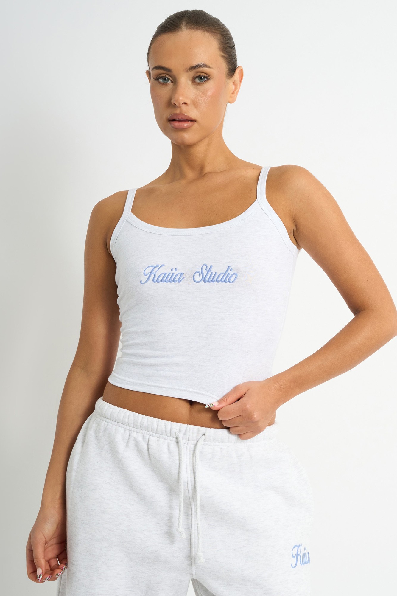 Light grey marl cami top featuring a vintage blue "Kaiia Studio" script logo, made from soft material with thin straps, styled with matching sweatpants.