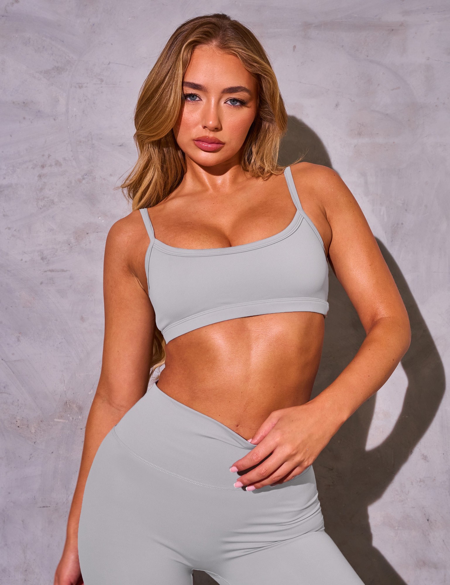 Dove grey Kaiia Sculpt Scoop Neck Bralette featuring thin straps and a smooth, stretchy fabric, paired with matching high-waisted leggings.