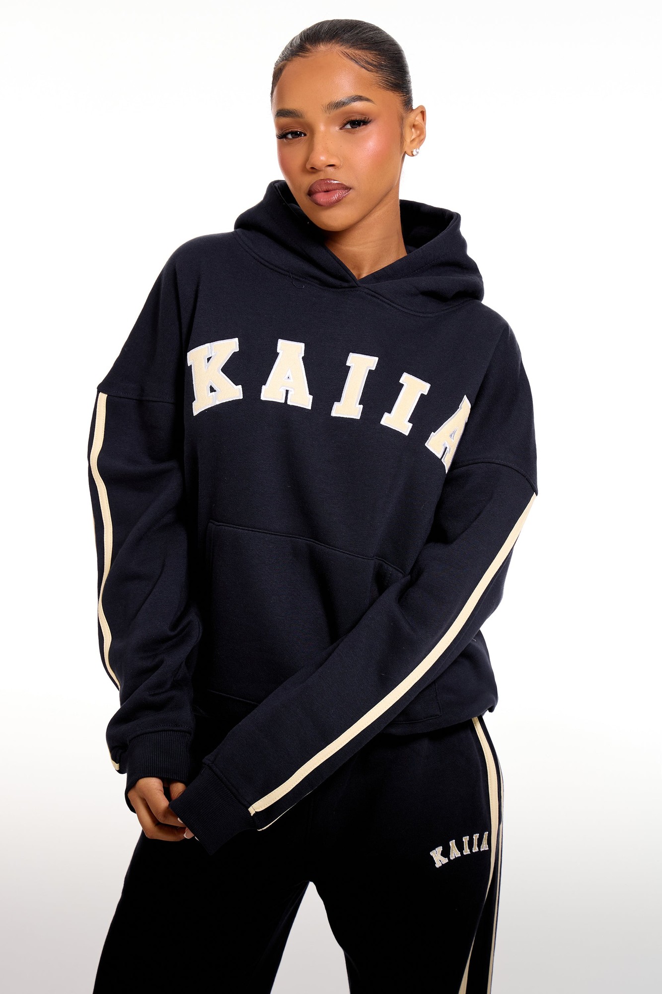 Oversized ink blue hoodie featuring soft yellow side stripes and "KAIIA" slogan across the chest, made from a comfortable material, styled with a relaxed fit.