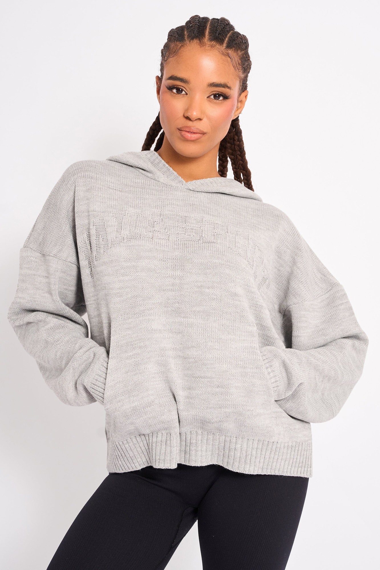 Soft grey knitted hoodie featuring a relaxed fit, oversized silhouette, and a hood, with ribbed cuffs and hem, worn by a model with braided hair.