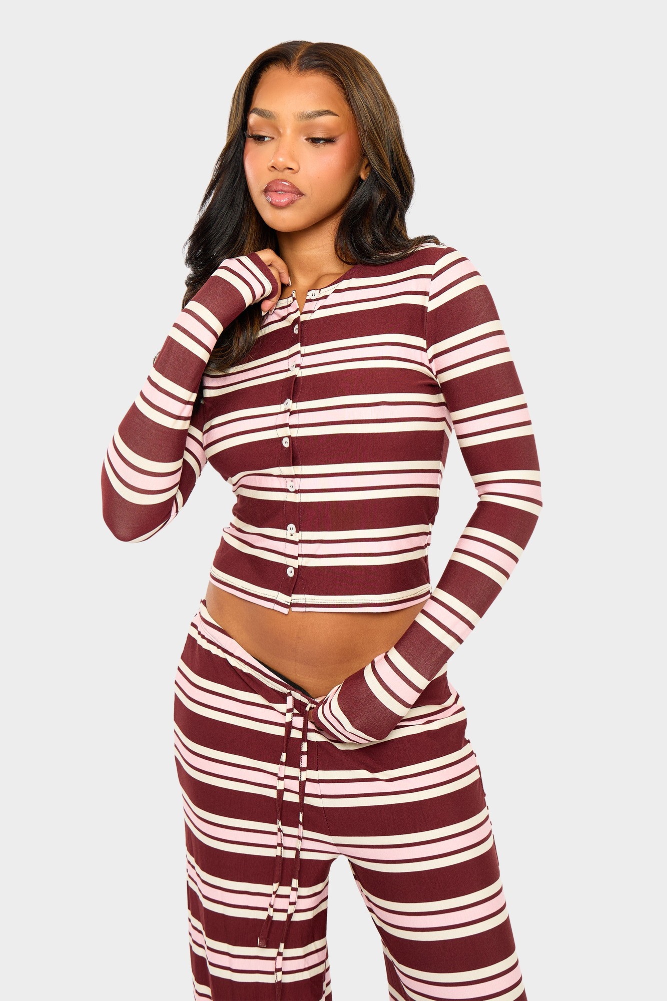 Burgundy and pink striped long sleeve crop top featuring a button-up front and fitted design, made from a soft, stretchy material.