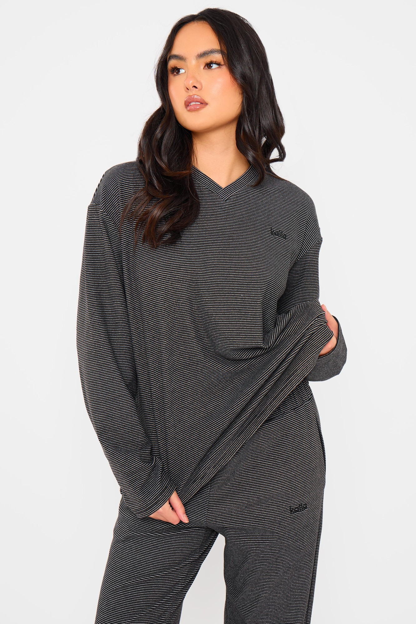 Oversized black and cream striped fleece top with a V-neck, long sleeves, and subtle branding on the chest, styled casually with a relaxed fit.