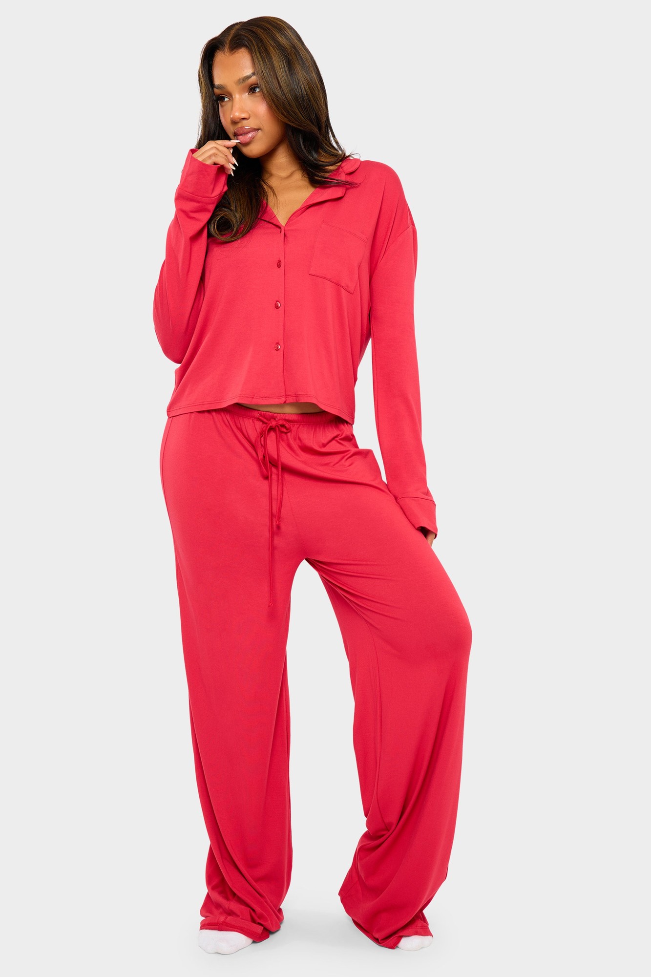Red supersoft slouchy pyjama trousers featuring a relaxed fit, drawstring waist, and paired with a matching long-sleeve button-up top.