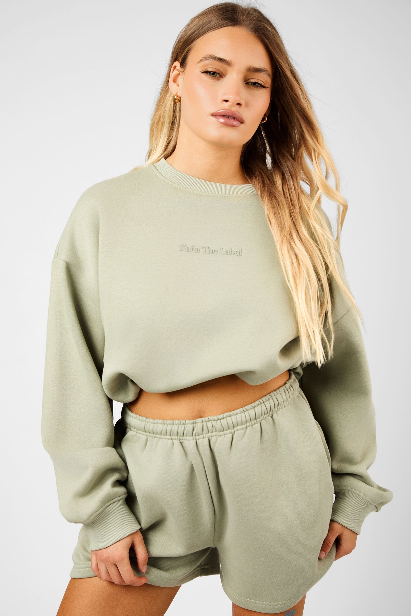 Sage green cropped sweatshirt with a bubble hem, featuring a relaxed fit, long sleeves, and subtle branding "Kaiia The Label" on the front.