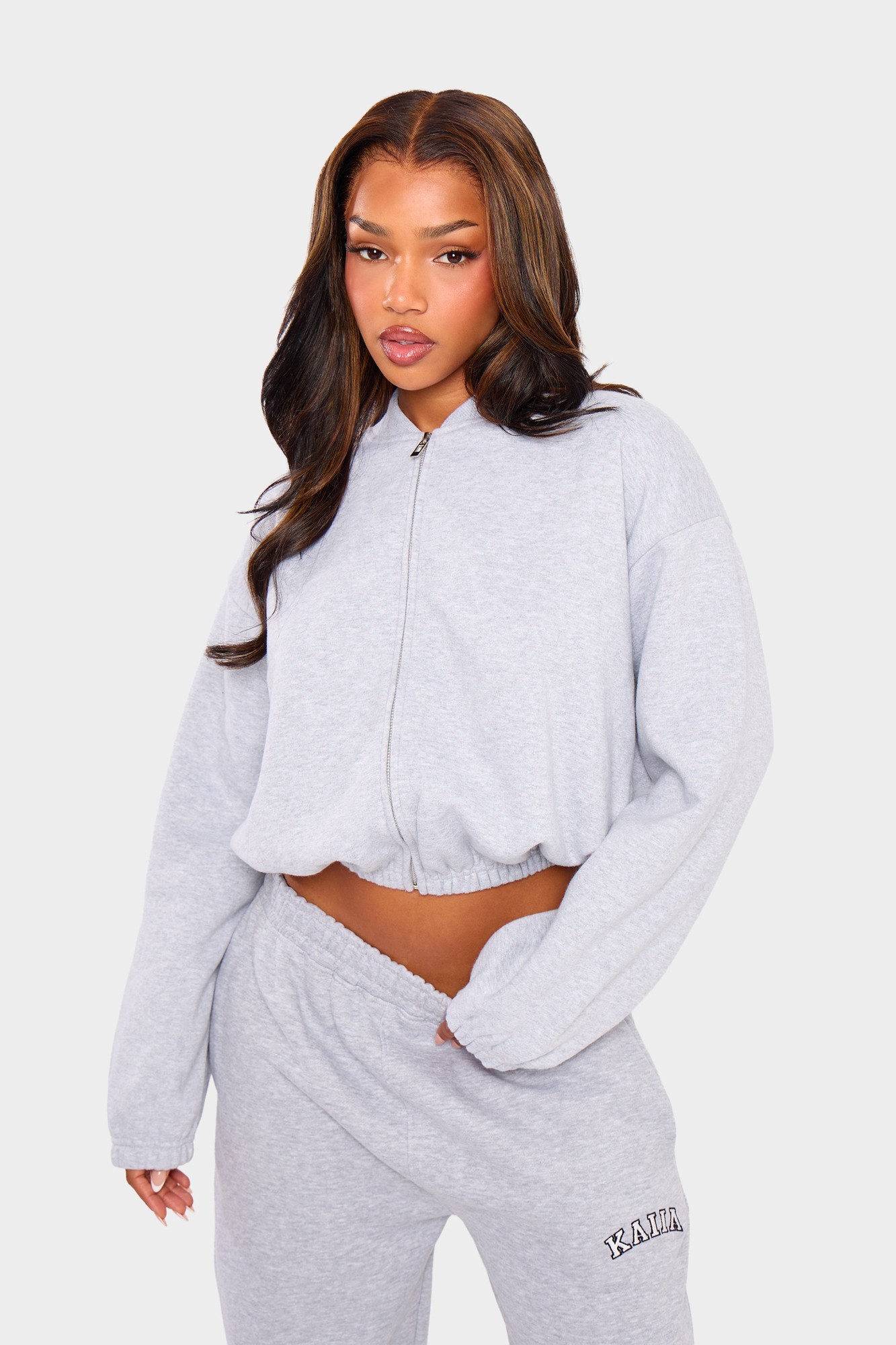 Light grey marl bomber-style sweatshirt with a zip closure, featuring a cropped fit and long sleeves, styled with matching sweatpants.