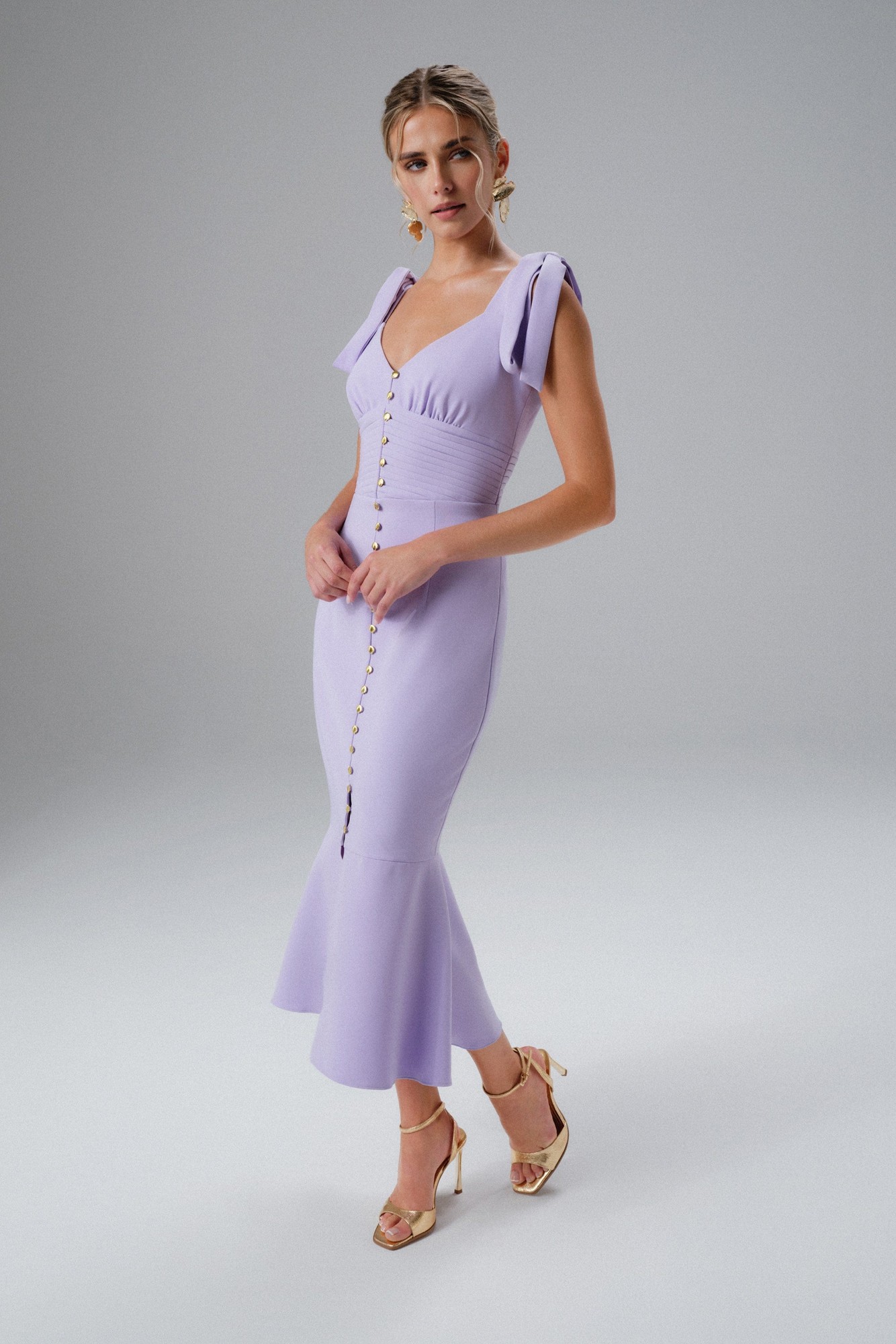 Lilac midi dress with tie straps, a fitted bodice, and a flared hem, featuring a button-down front and a sleek, stretchy material.