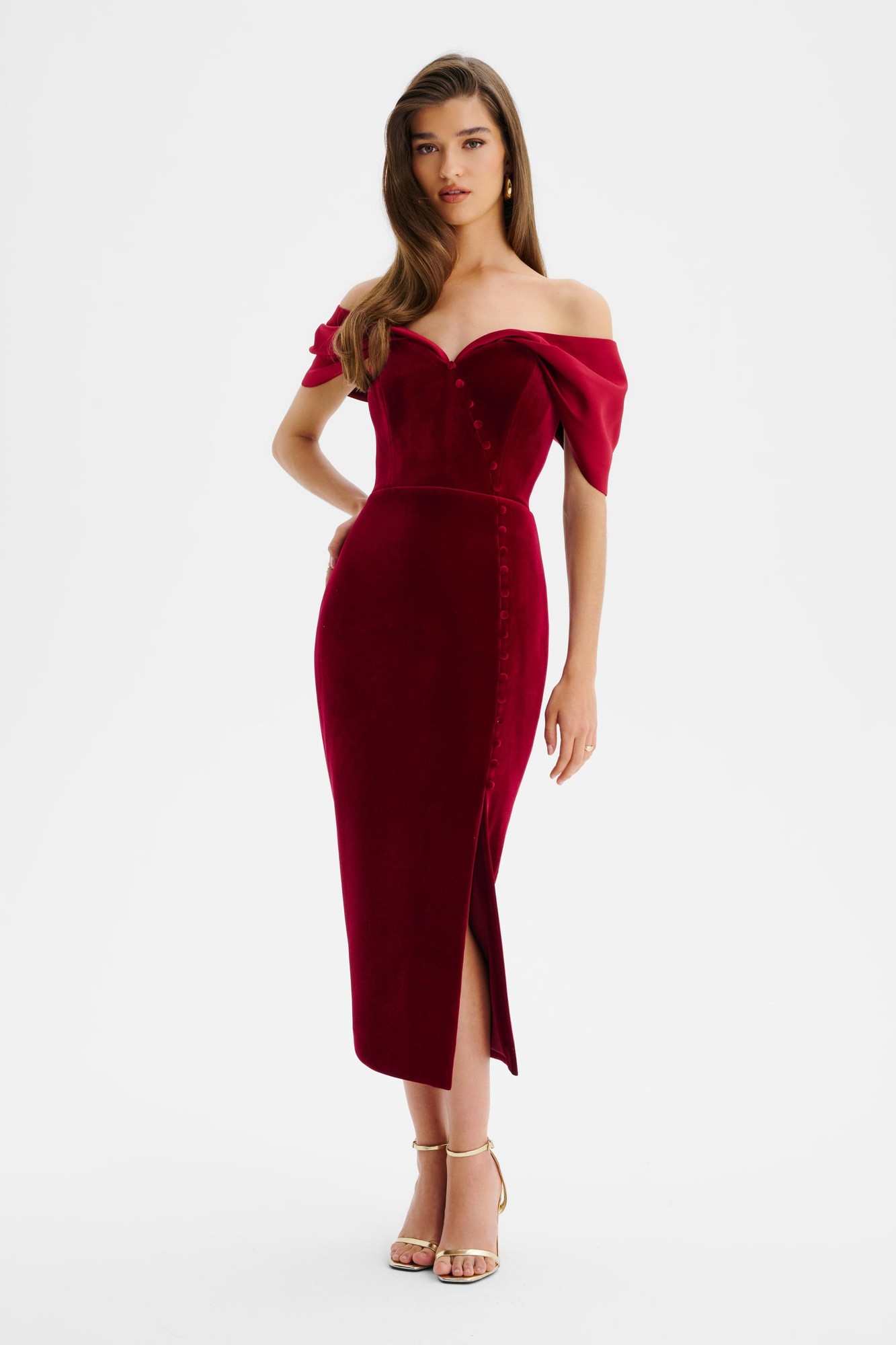 Burgundy velvet satin mix midi dress featuring an off-the-shoulder Bardot neckline, fitted bodice, and a side slit with button detailing, styled with strappy heels.