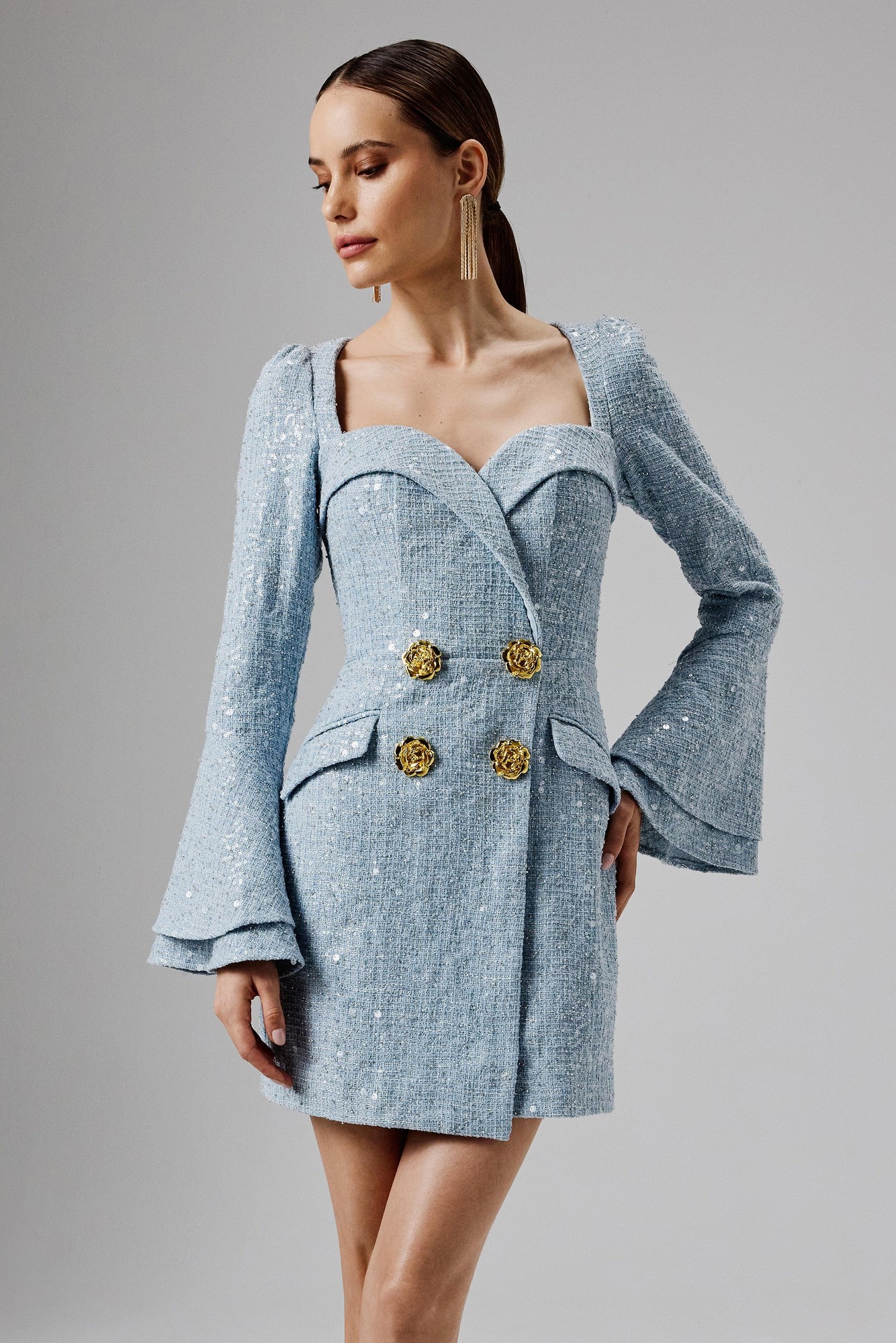 Oversized blue boucle blazer mini dress featuring a deep V-neck, long bell sleeves, and gold rose button details, designed for a chic and elegant look.