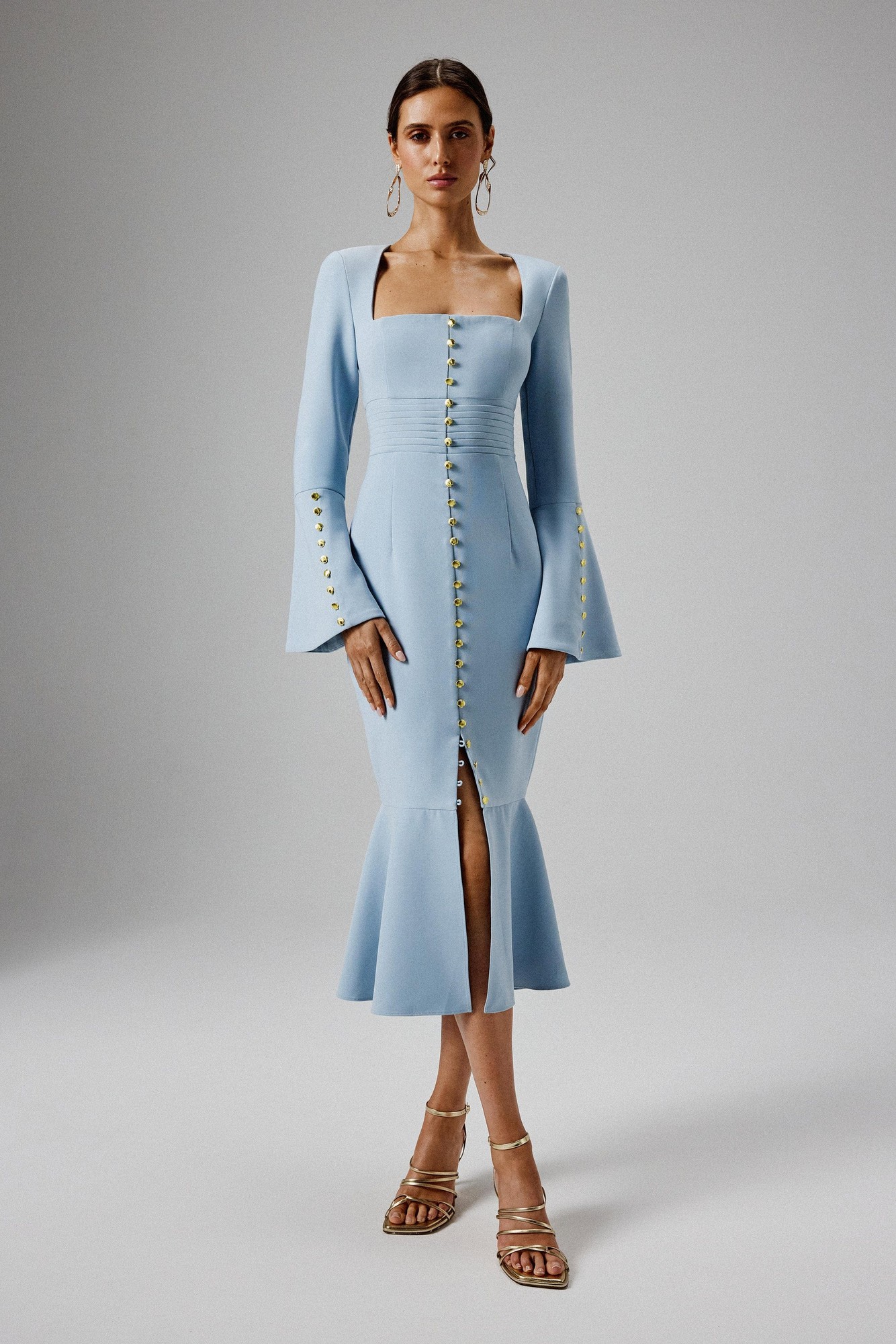 Light blue midi dress with fluted sleeves, square neckline, and a front slit, featuring a row of decorative buttons down the center.