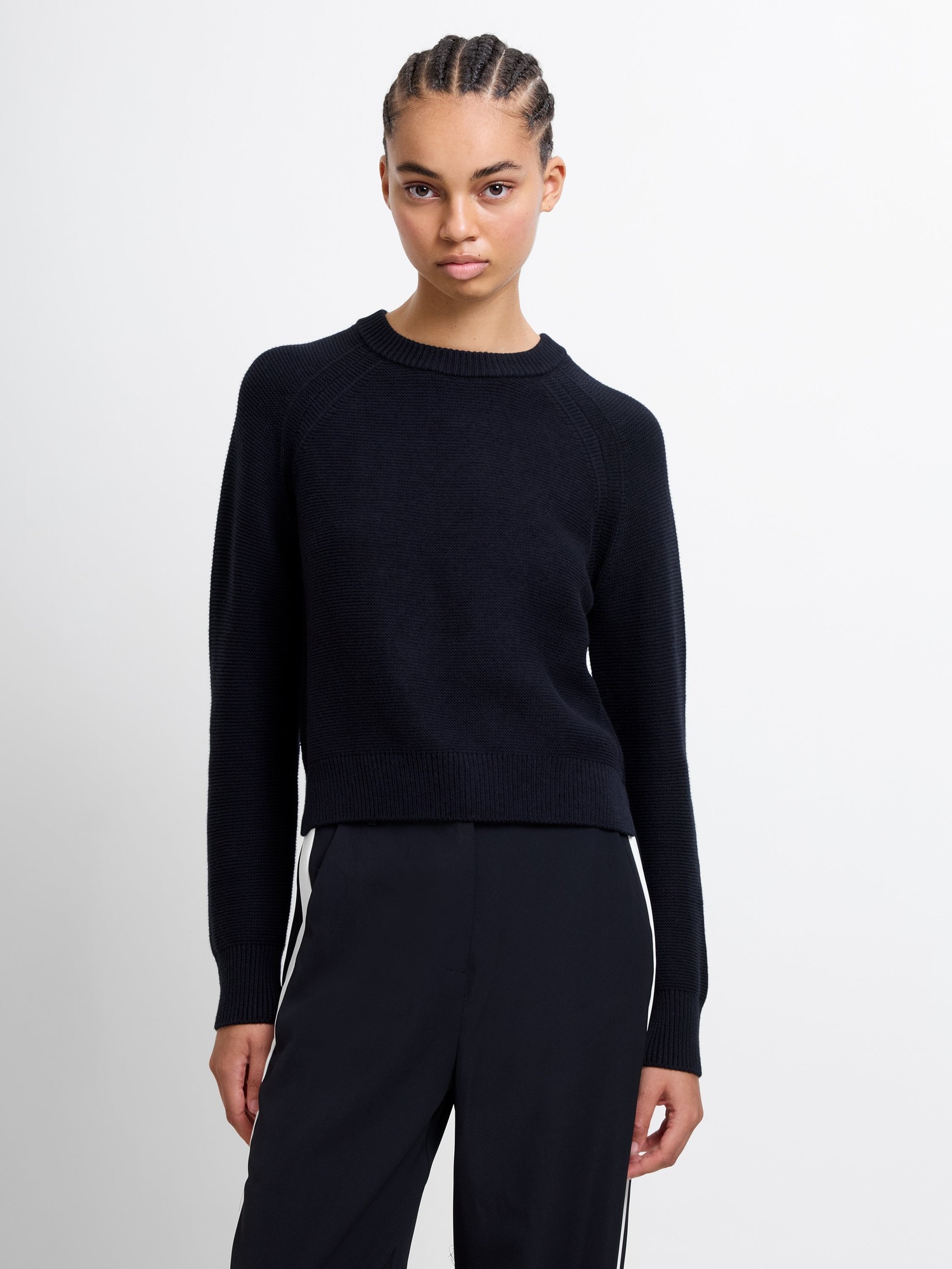 Black crew neck jumper by French Connection, featuring a ribbed texture, long raglan sleeves, and a cropped fit, styled with a model against a plain background.