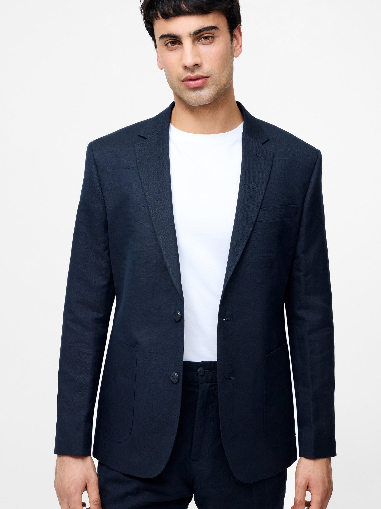 Navy linen suit jacket featuring a single-breasted design, notch lapels, two front pockets, and a tailored fit, paired with a plain white t-shirt.