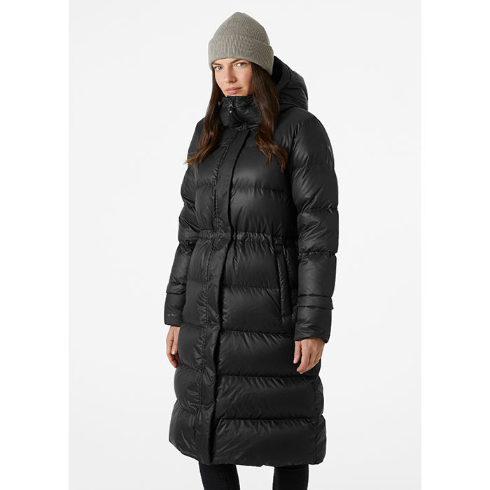 Black long puffer jacket with a belted waist, featuring a high collar and hood, paired with a gray knit beanie, ideal for cold weather.