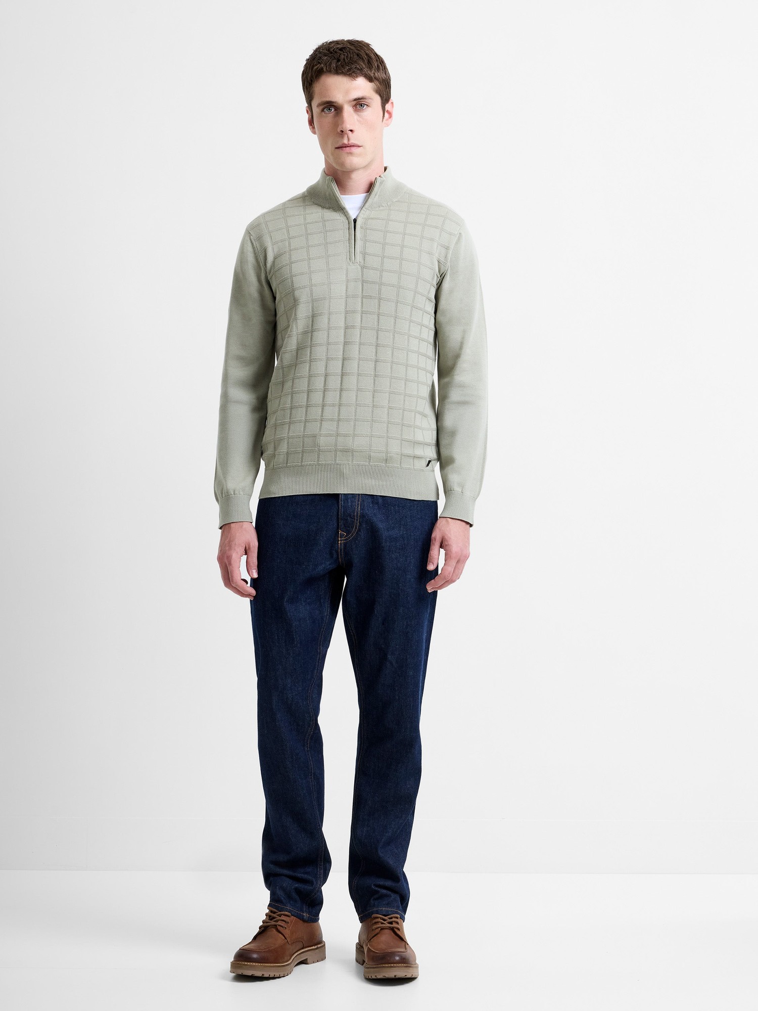 Mint green 1/2 zip knit jumper with a textured grid pattern, featuring a stand-up collar, paired with dark blue jeans and brown shoes.