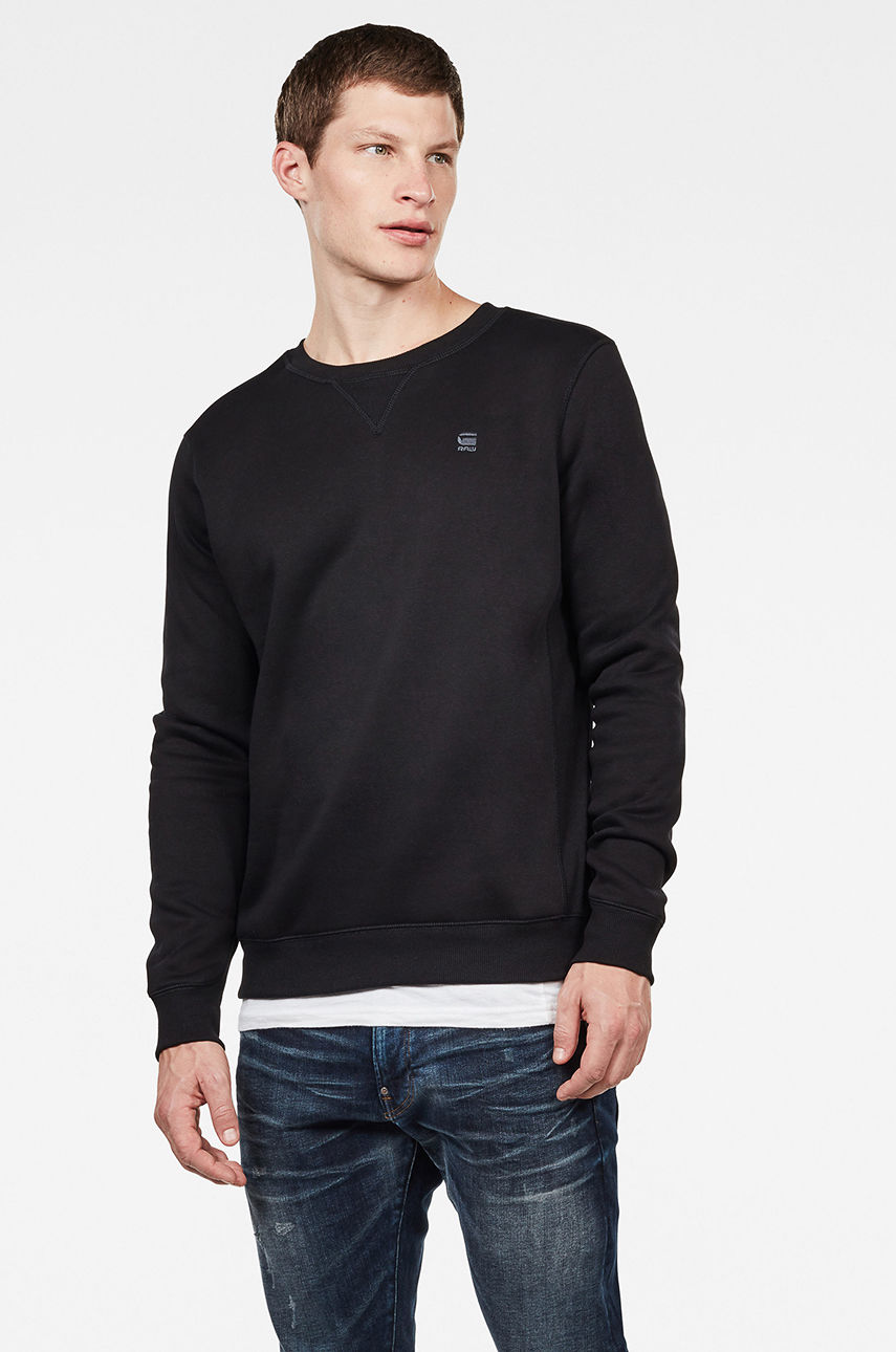 Black long sleeve sweatshirt made from soft material, featuring a crew neck and a small G-Star logo on the chest, paired with blue jeans for a casual look.