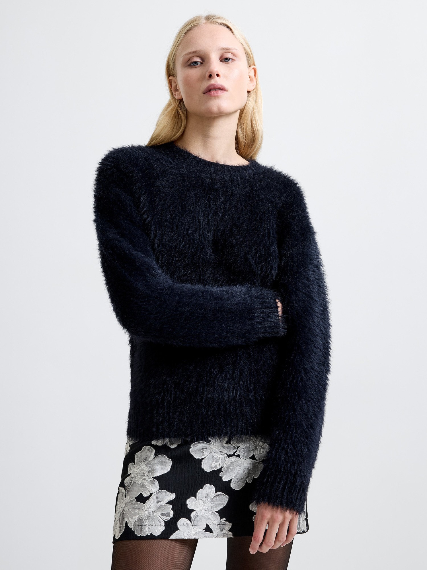 Navy fluffy knit jumper with a mock neck, featuring long sleeves and a relaxed fit, paired with a black floral skirt for a stylish look.