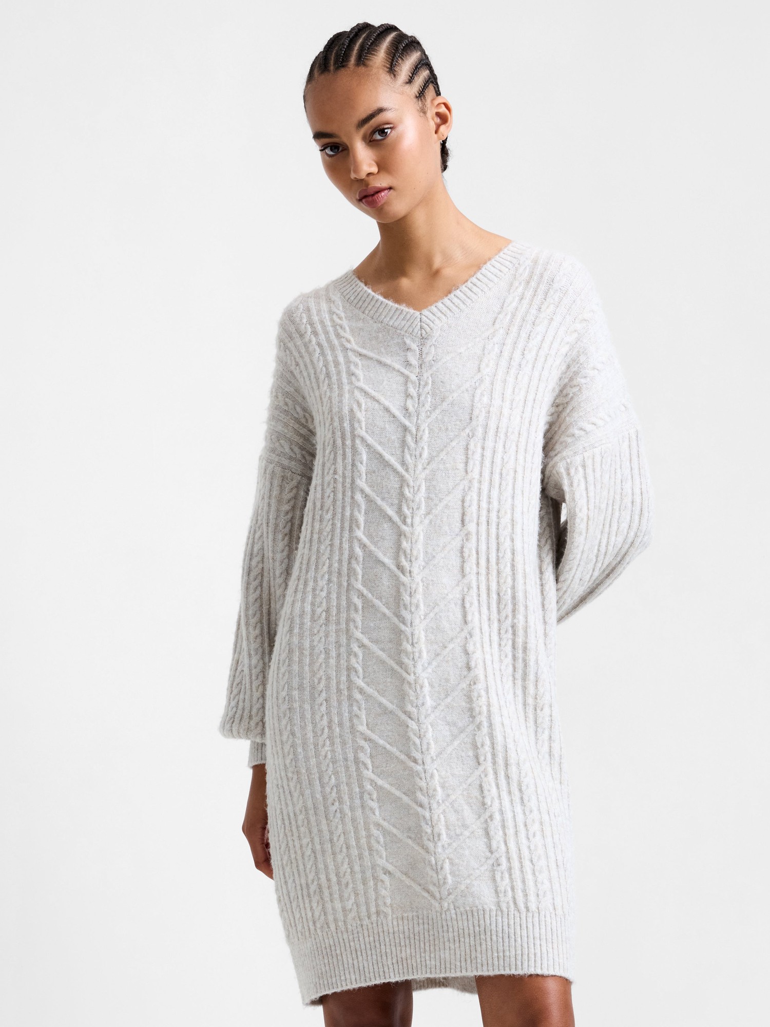 Light grey cable knit jumper dress with a V-neck, oversized sleeves, and a relaxed fit, made from a soft, textured fabric.