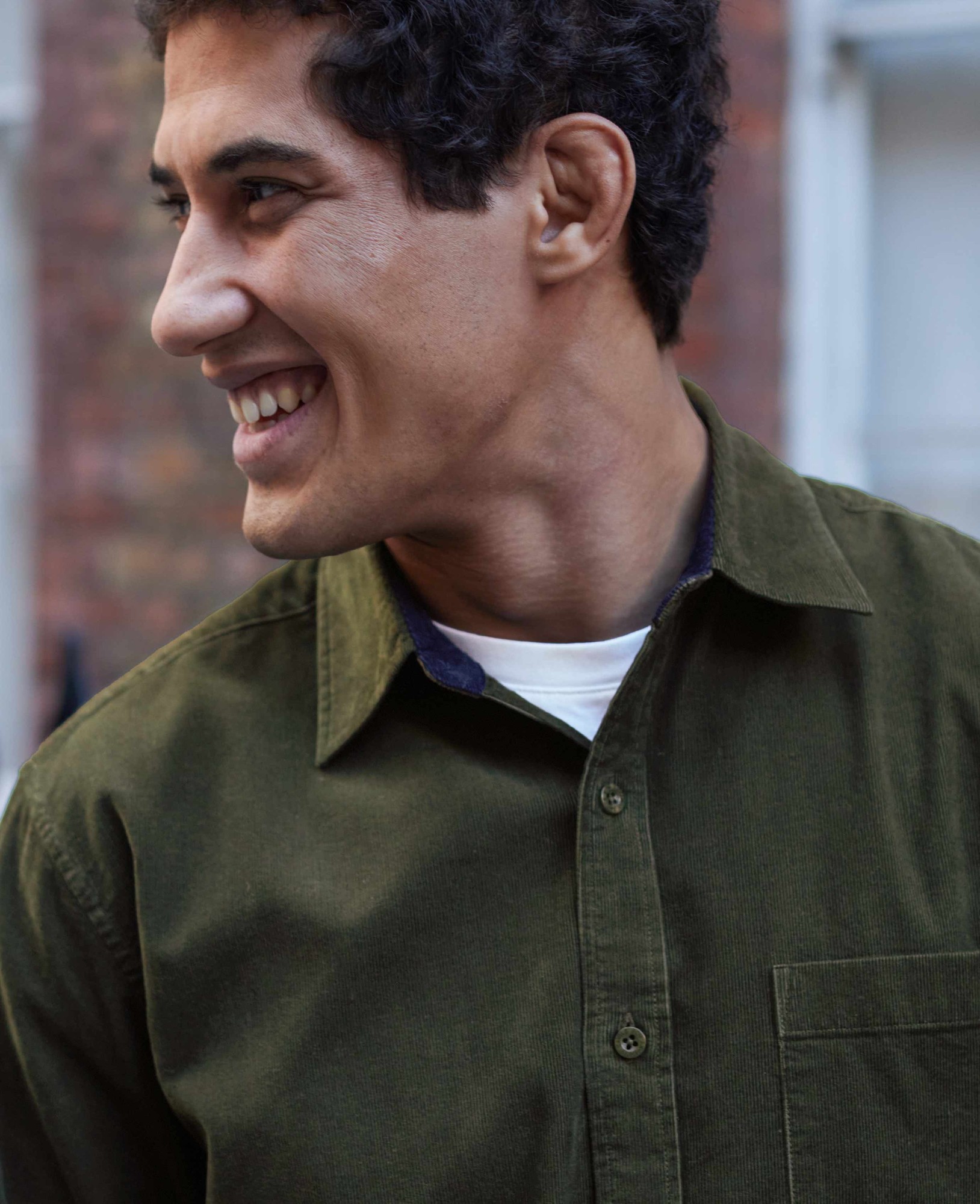 Men's khaki cotton babycord shirt in classic fit, featuring a button-down collar, chest pocket, and a soft textured fabric, modelled by a smiling man.