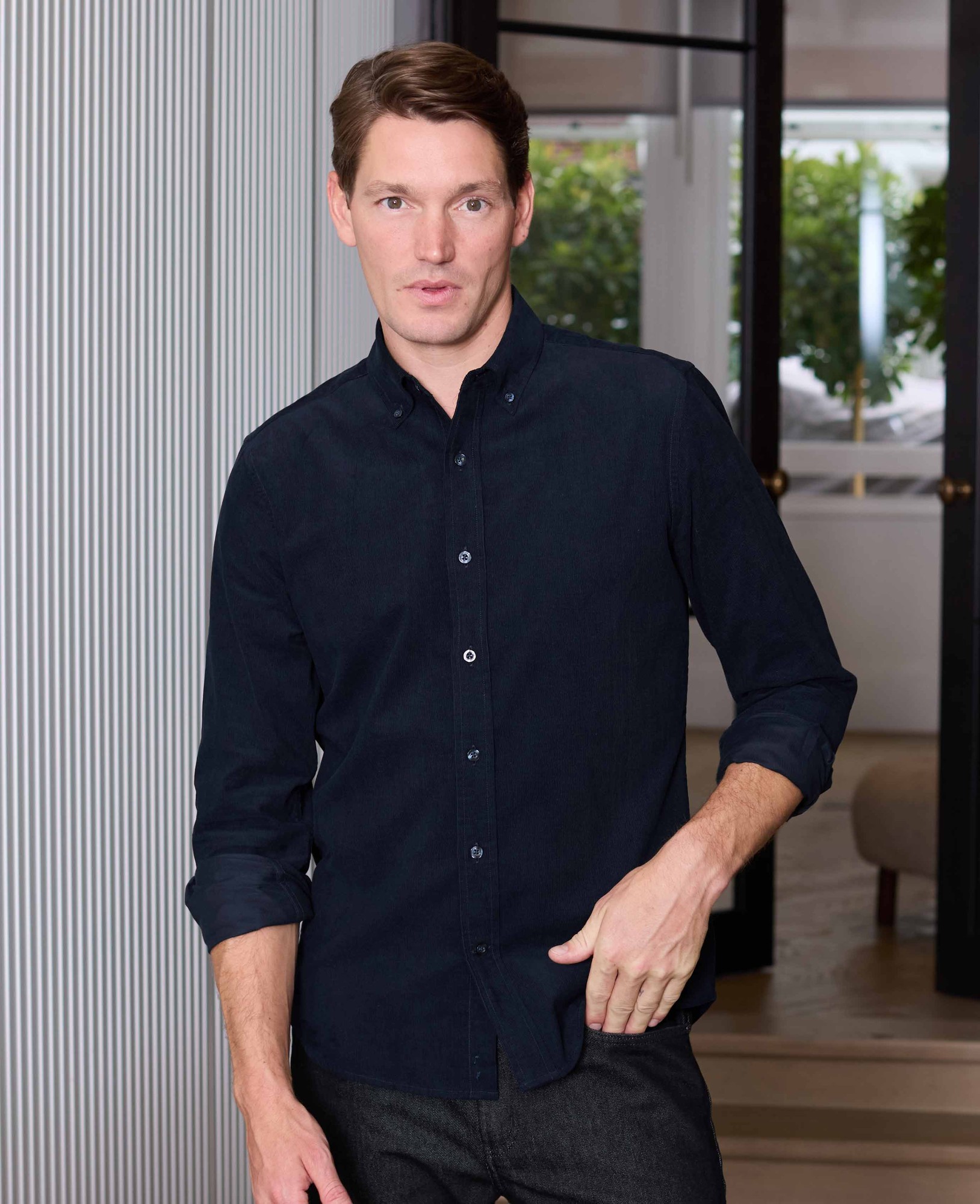 Men's navy cotton babycord shirt in classic fit, featuring a button-down collar and long sleeves, displayed on a model in a stylish indoor setting.