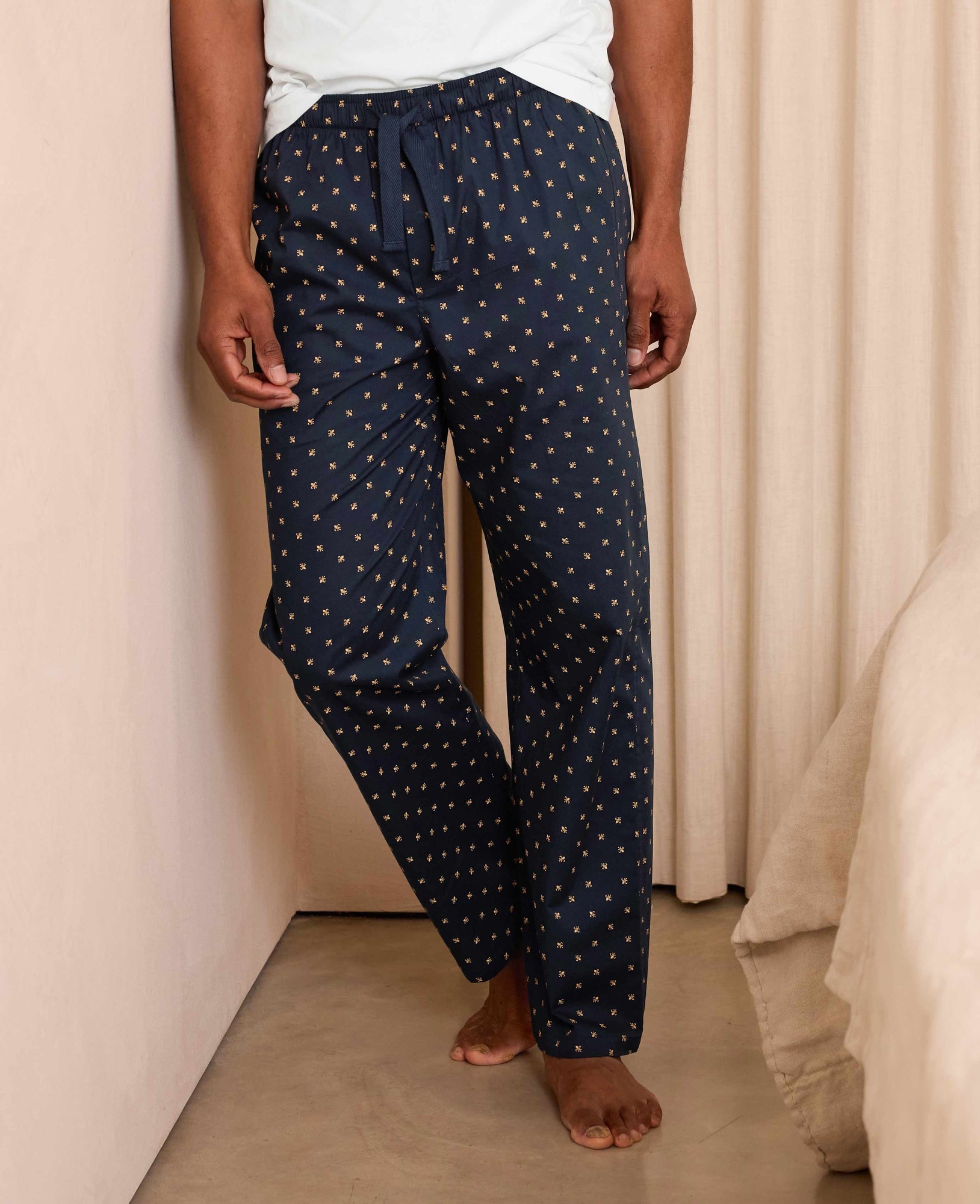 Men's large lounge pants in navy cotton featuring a fleur de lys pattern in gold, with an elastic waistband and drawstring, styled for comfort and relaxation.