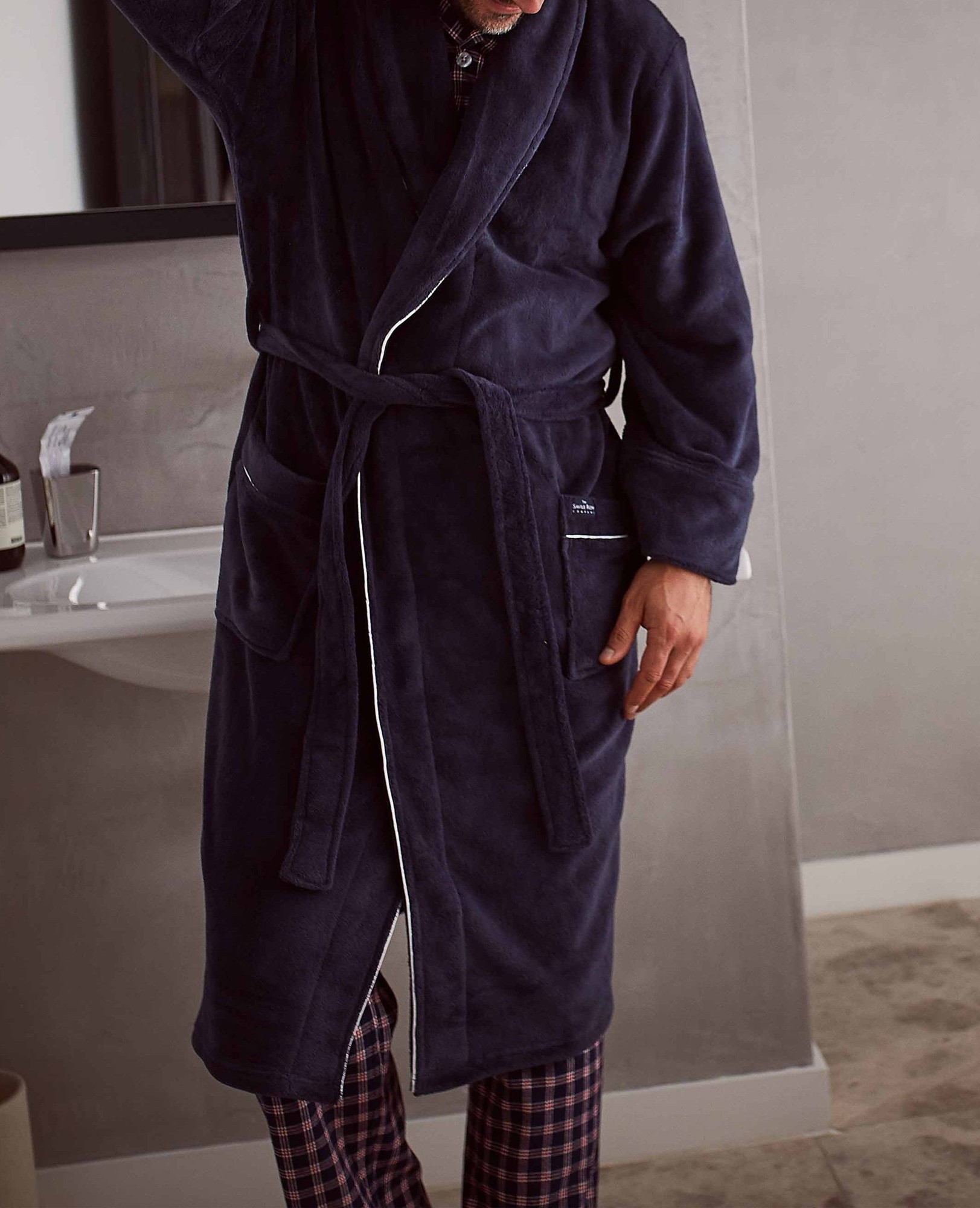Men's medium navy fleece dressing gown with white piping, featuring a belt, two front pockets, and a soft texture, perfect for comfort and style.
