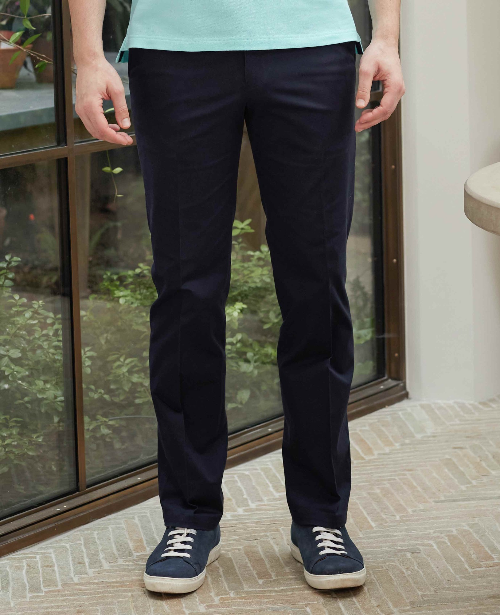 Men's navy stretch cotton chinos in a classic fit with a flat front, featuring a size of 32" x 34", paired with casual sneakers in a light setting.