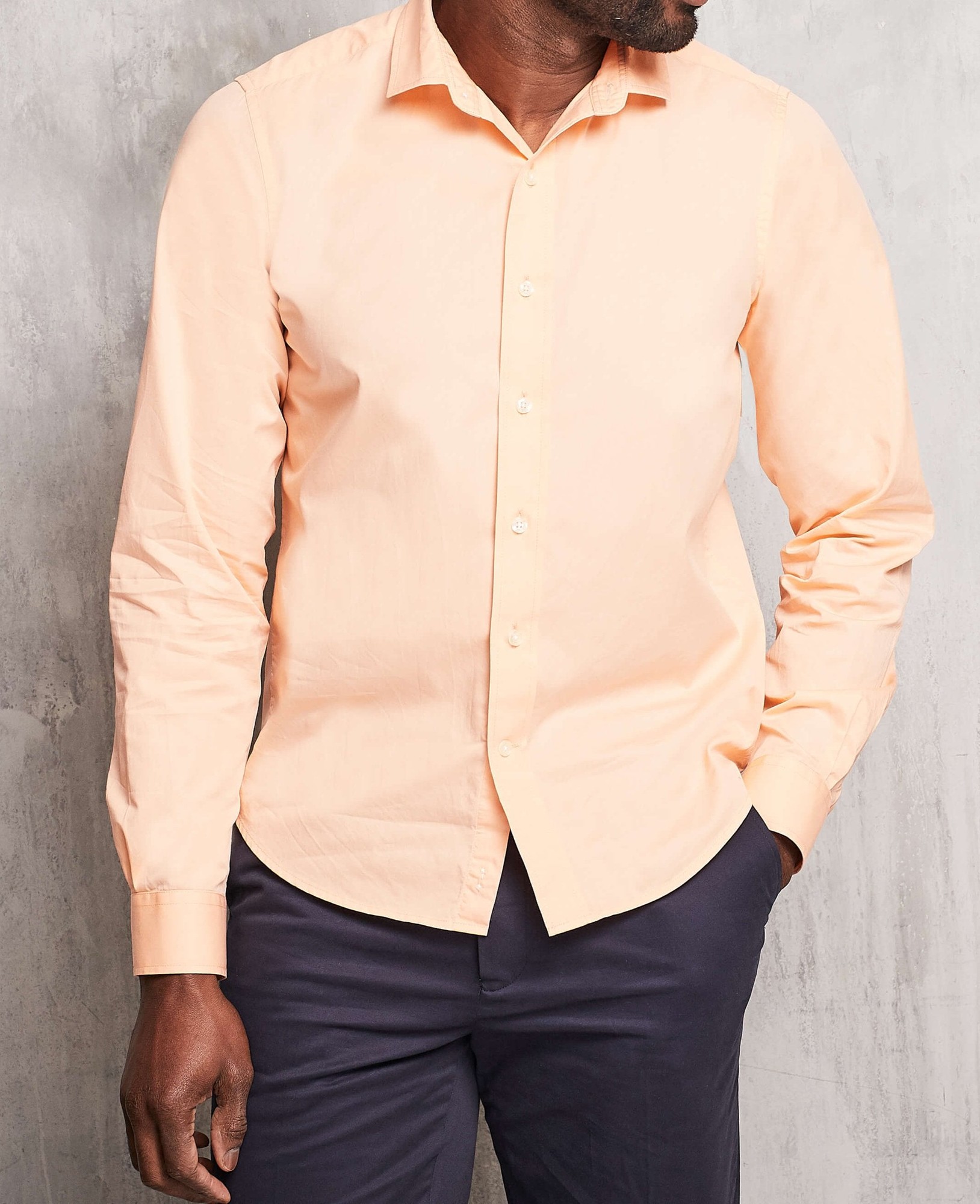 Men's peach twill slim fit shirt in shorter length, size Medium X Extra Long, featuring a button-down front and long sleeves, paired with dark trousers.