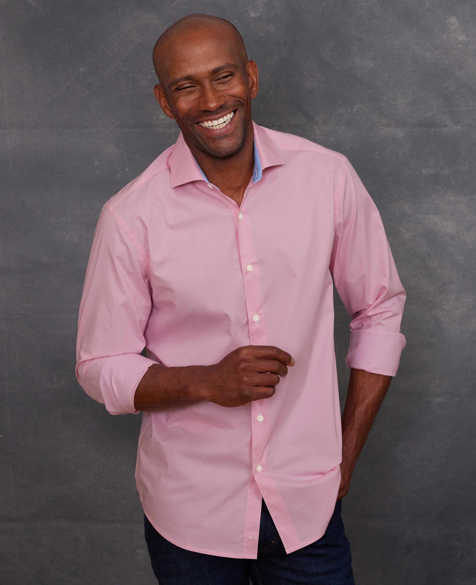 Men's slim fit smart-casual shirt in light pink cotton dobby, featuring single cuffs and a size of Large X Extra Long, modeled by a smiling man against a textured background.