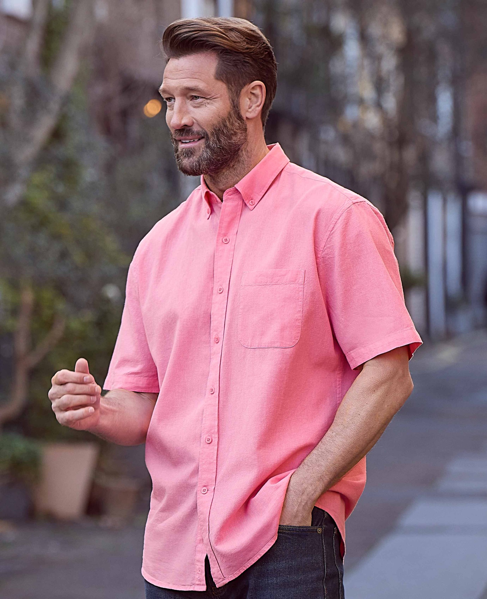 Classic fit short sleeve button-down shirt in pink, made from a linen-cotton blend, featuring a chest pocket and a relaxed style, worn by a man outdoors.