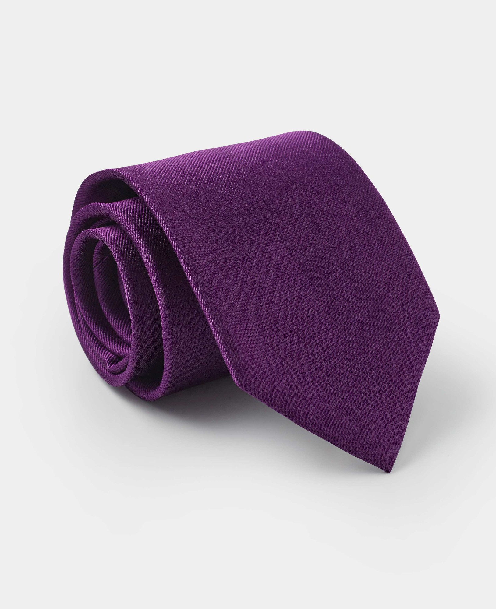 Plain twill silk tie in a rich purple hue, featuring a smooth texture and classic pointed end, elegantly rolled for display.