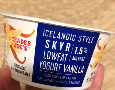 White cup featuring a blue label with yellow vanilla flower graphics, labeled "Icelandic Style Skyr Lowfat Yogurt Vanilla," emphasizing low milkfat and high protein content.