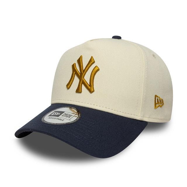 Cream-colored cap with a navy blue brim, featuring an embroidered gold New York Yankees logo on the front and a New Era tag on the side.
