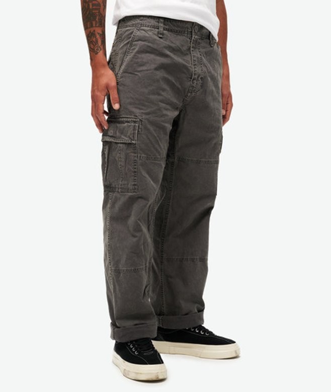 Baggy cargo trousers in dark gray organic cotton, featuring multiple side pockets and a relaxed fit, paired with black sneakers for a casual look.