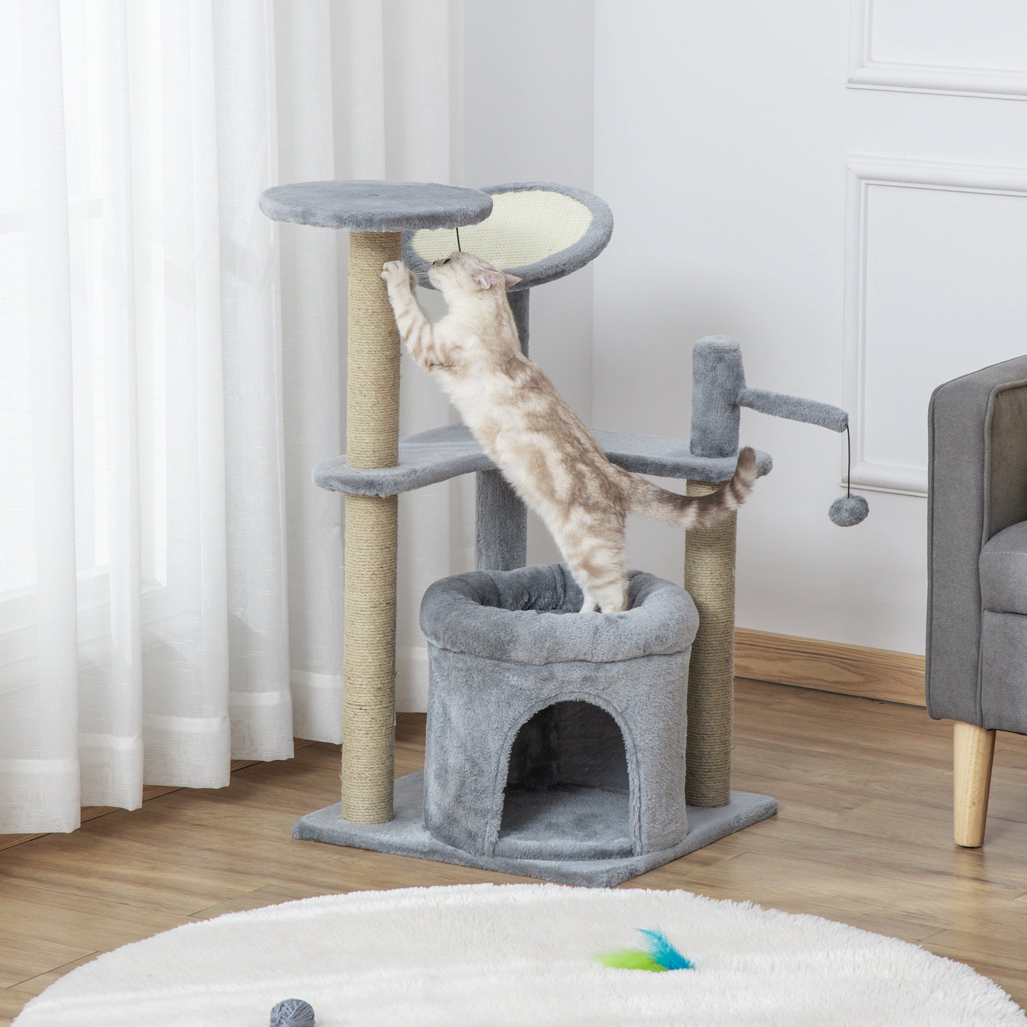 Grey cat tree tower with scratching posts, condo bed, perch, and hanging ball toy, featuring a soft fabric finish and a playful kitten climbing on it.