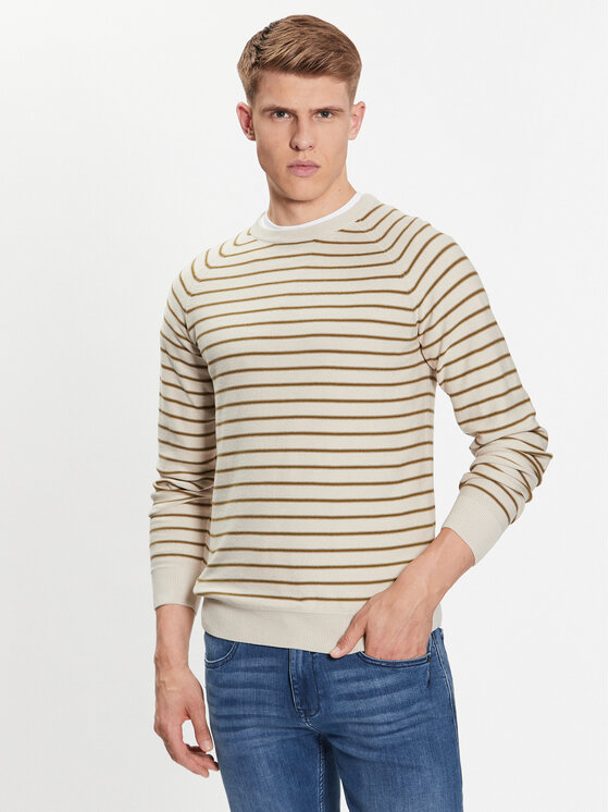 Cream pullover sweater with brown horizontal stripes, crew neck, and ribbed cuffs, paired with blue jeans, showcasing a casual, stylish look.