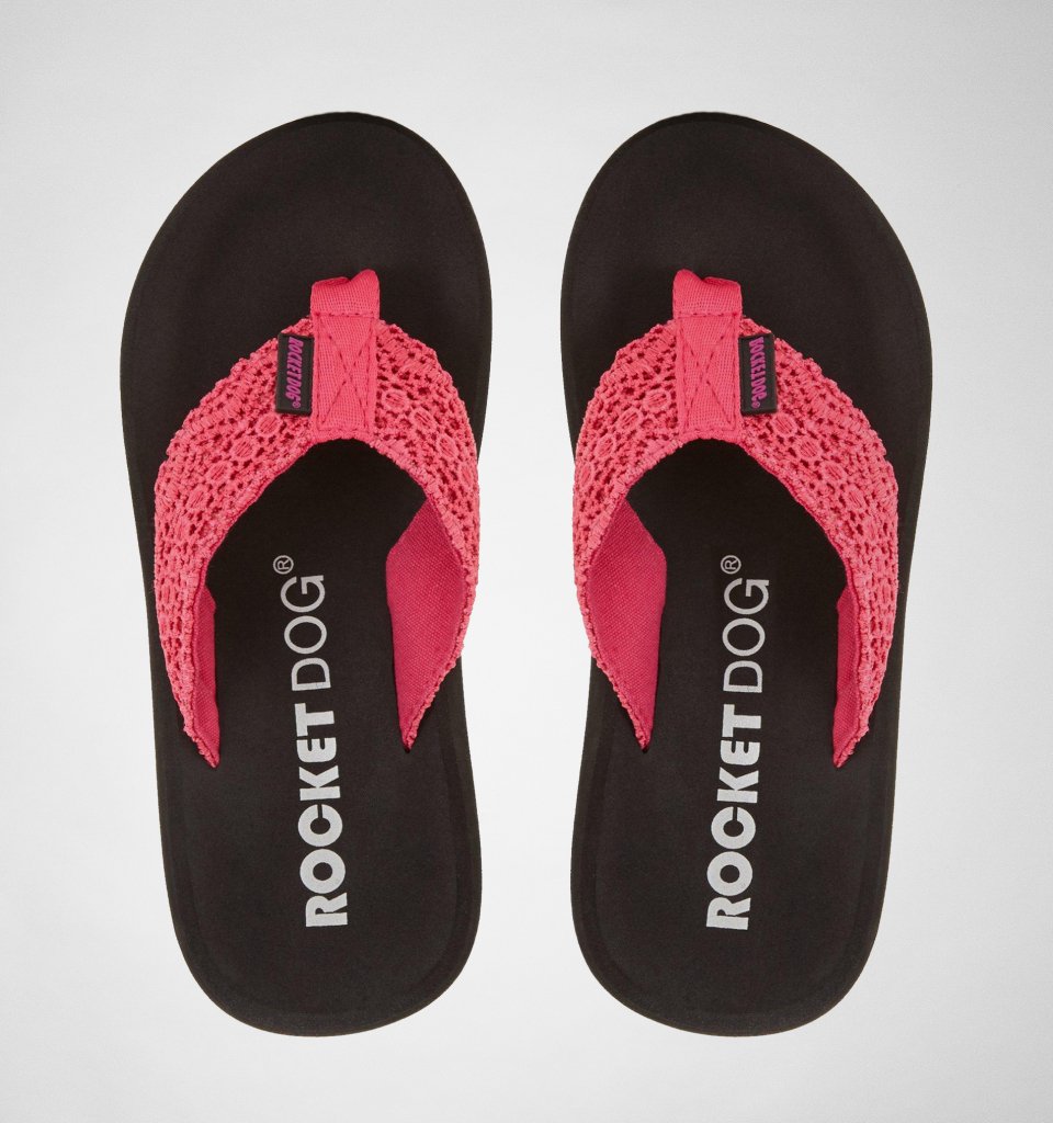 Pink fabric flip flops with a textured crochet strap and cushioned black sole, featuring the Rocket Dog logo prominently displayed on the footbed.