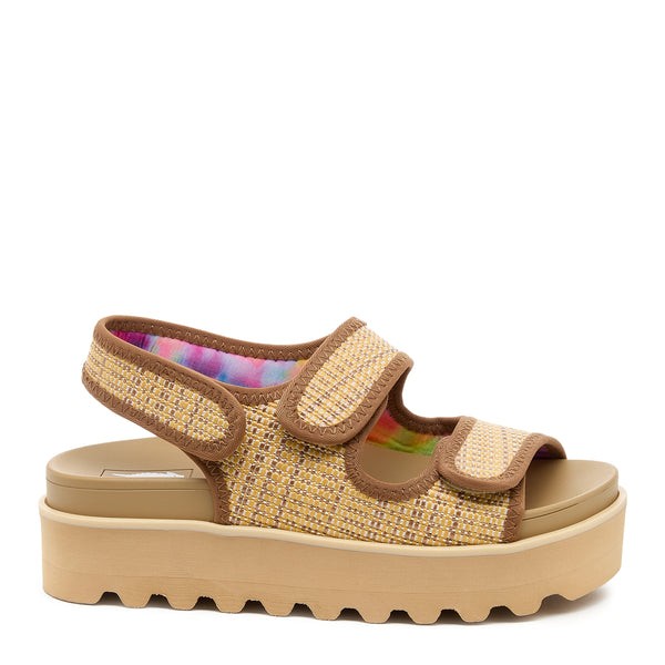 Natural raffia sandal featuring a woven upper in beige with brown accents, adjustable Velcro straps, and a chunky platform sole in light tan.