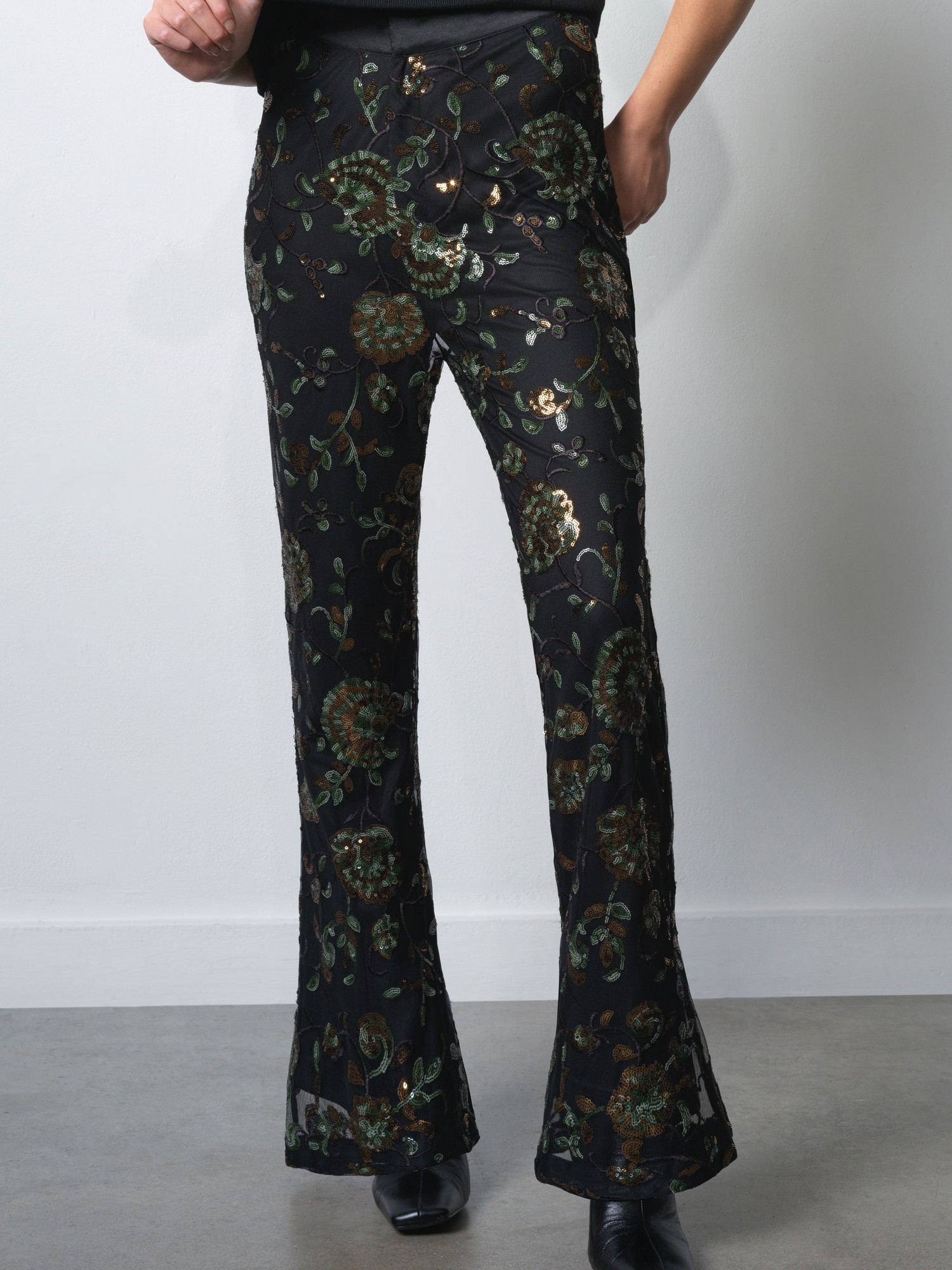 Black sequin flare trousers featuring intricate floral patterns in gold and green, designed by French Connection, with a fitted waist and flared hem.