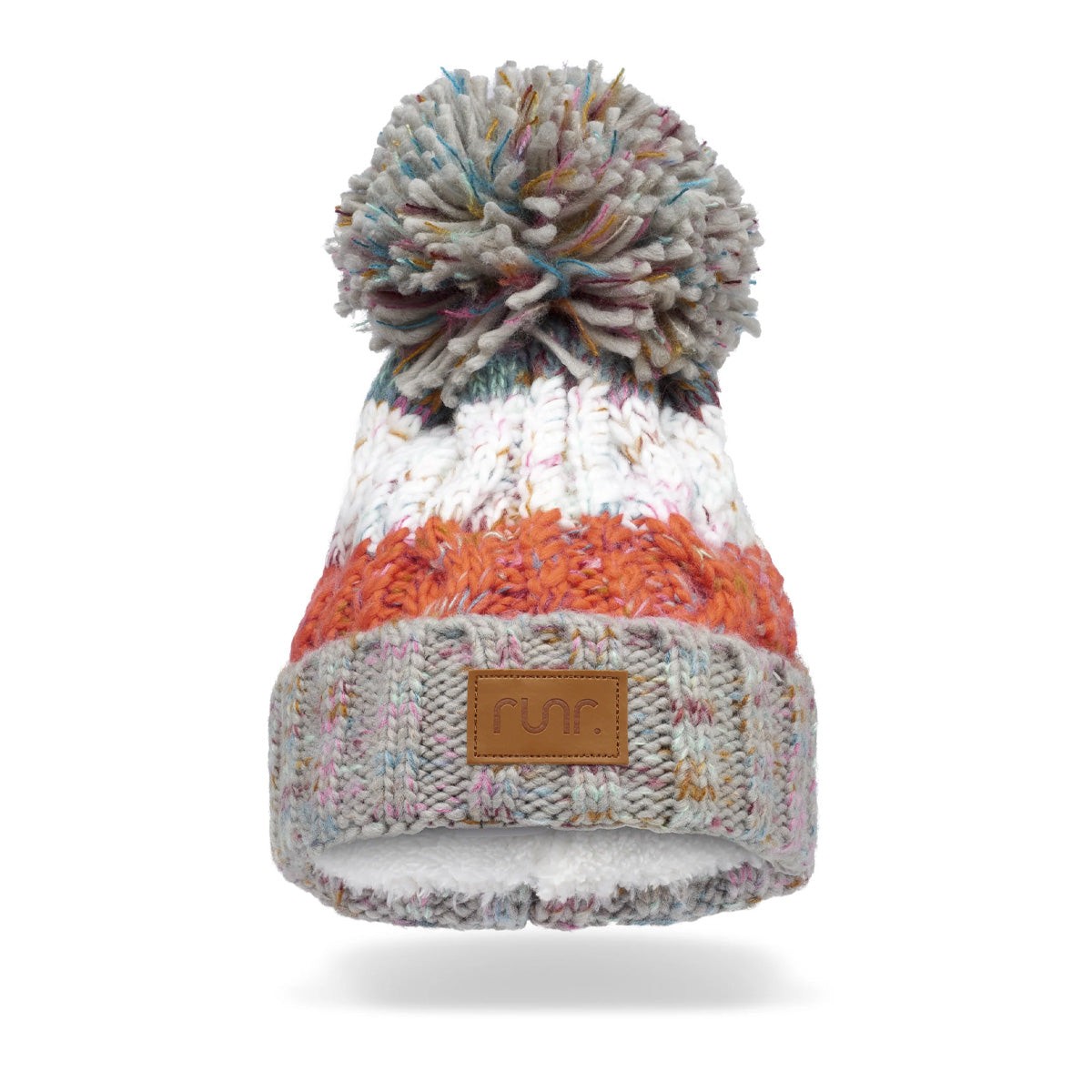A cozy knitted winter bobble hat featuring a rainbow pattern with shades of white, orange, and grey, topped with a large pom-pom and a leather "Runr" tag on the cuff.