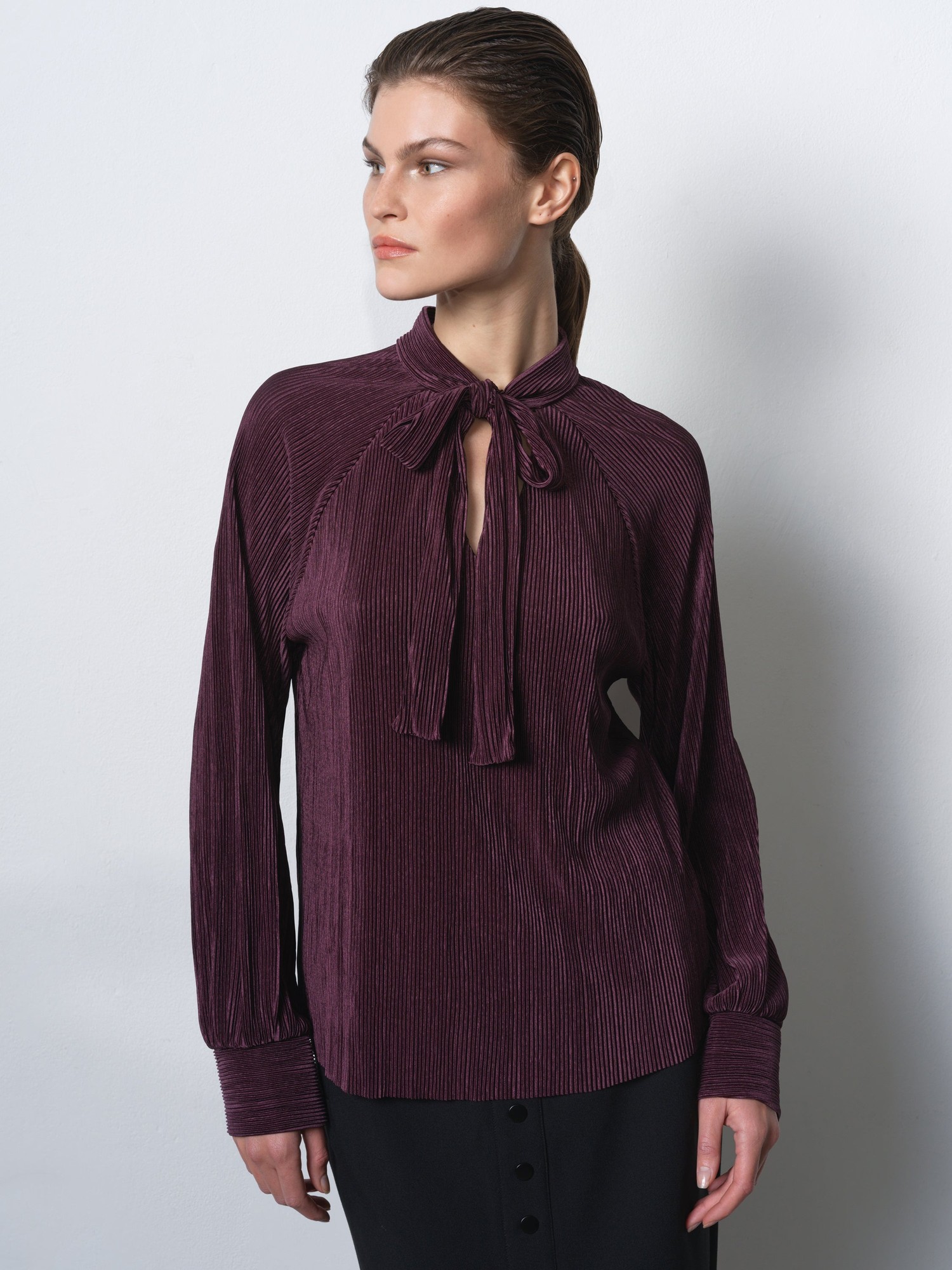 Long-sleeve, deep plum plisse shirt featuring a tie neck and subtle vertical stripes, styled with a relaxed fit and buttoned cuffs.