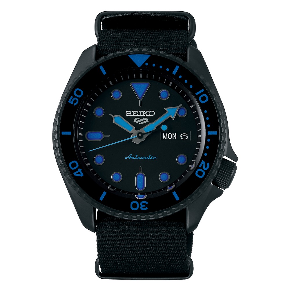 Black Seiko 5 Sports automatic watch with a black nylon strap, blue accents on the dial, luminous hour markers, and a day-date display at 3 o'clock, water-resistant up to 100 meters.