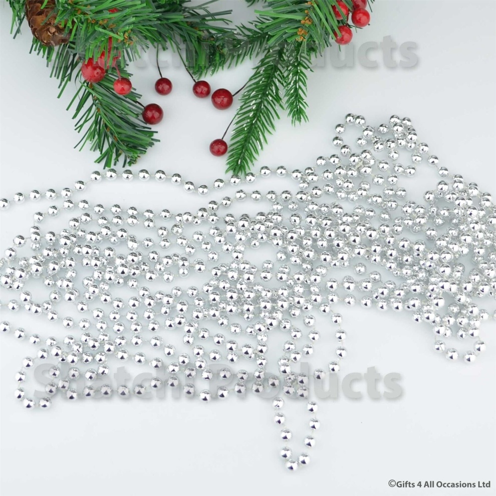 Silver 24ft hanging bead garland made of shiny tinsel, featuring small round beads, perfect for Christmas tree decorations and festive parties, with green pine branches and red berries in the background.