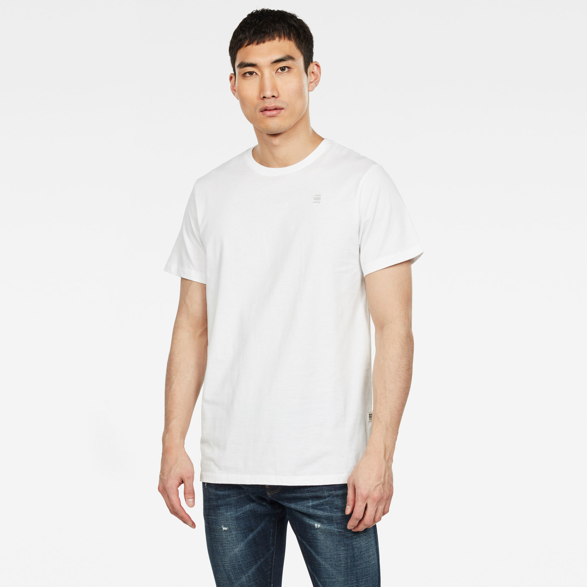 White short sleeve T-shirt by G-Star, made of soft cotton, featuring a round neckline and a subtle logo on the chest, paired with dark blue jeans.