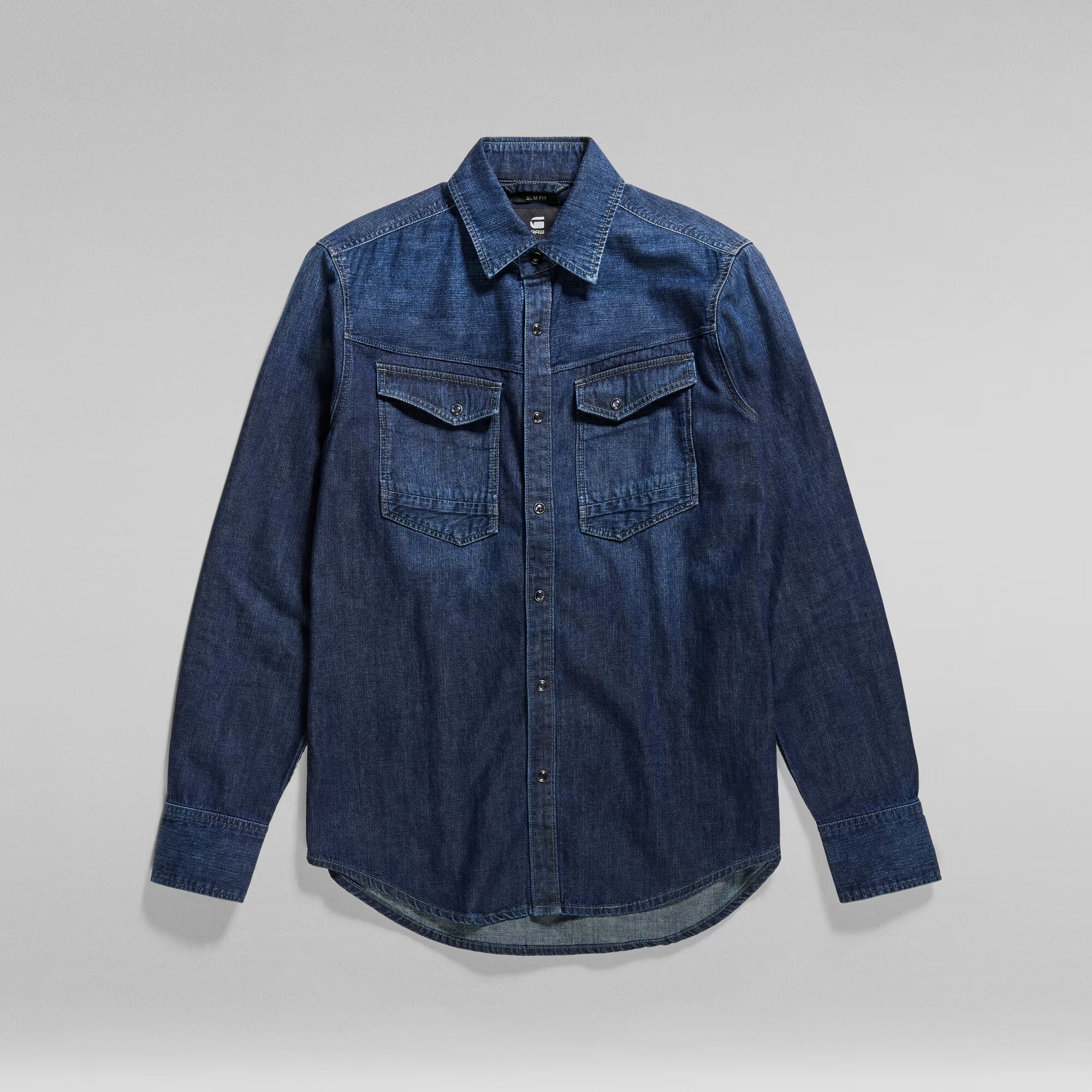 Slim-fit denim overshirt in dark blue, featuring a classic collar, two chest pockets, button closure, and long sleeves with buttoned cuffs.
