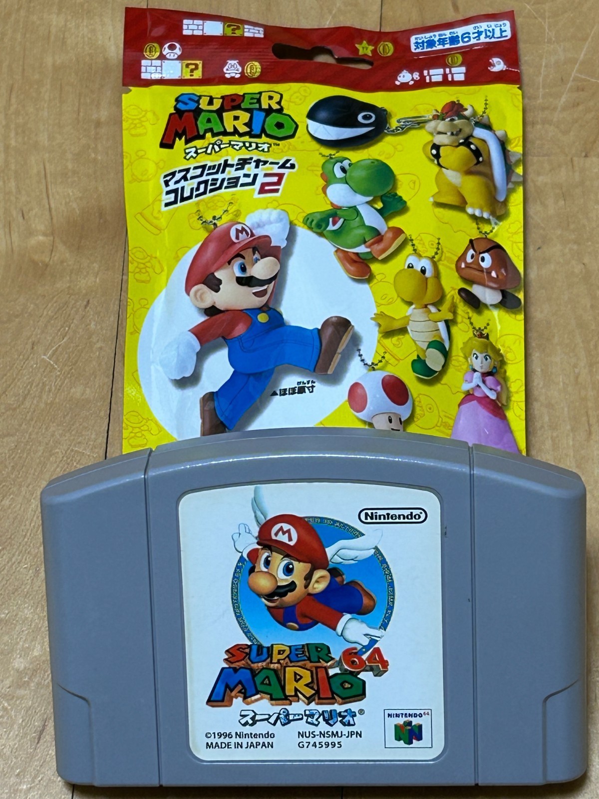 Super Mario mascot keyring featuring a colorful Mario design, attached to a vibrant yellow packaging showcasing various characters from the Super Mario series.