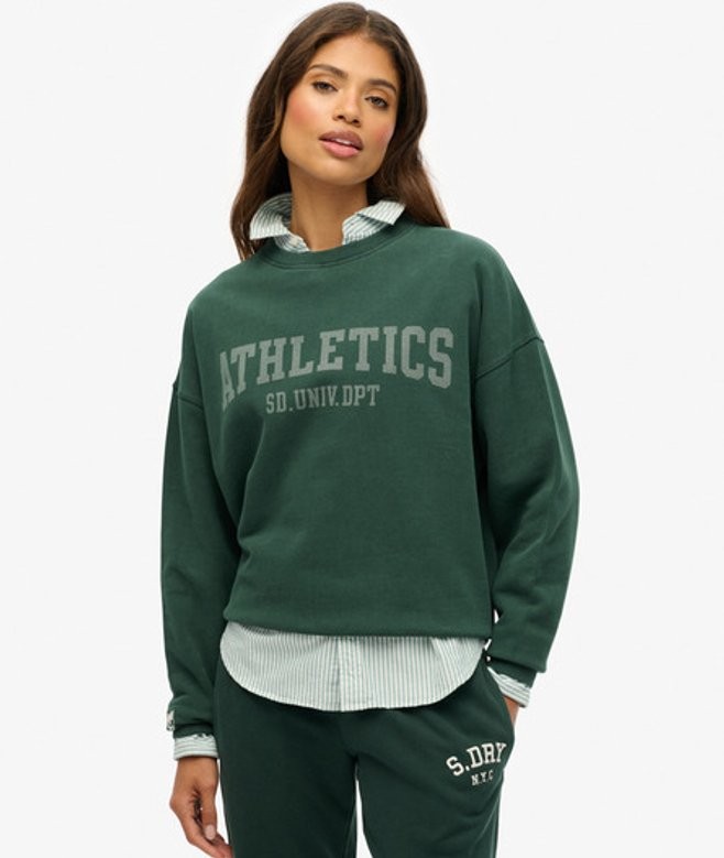 Green relaxed crew sweatshirt featuring "ATHLETICS" in bold gray letters, paired with a striped shirt underneath, made from soft material for comfort.