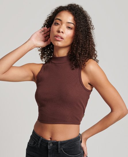 Brown high-collar tank top for women by Superdry, featuring a fitted design and sleeveless style, paired with black jeans and styled with natural, curly hair.