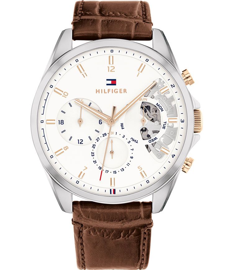 Men's Tommy Hilfiger Baker watch featuring a 44mm silver dial, brown leather strap, gold-tone hands, and multifunction subdials with a skeleton detail.