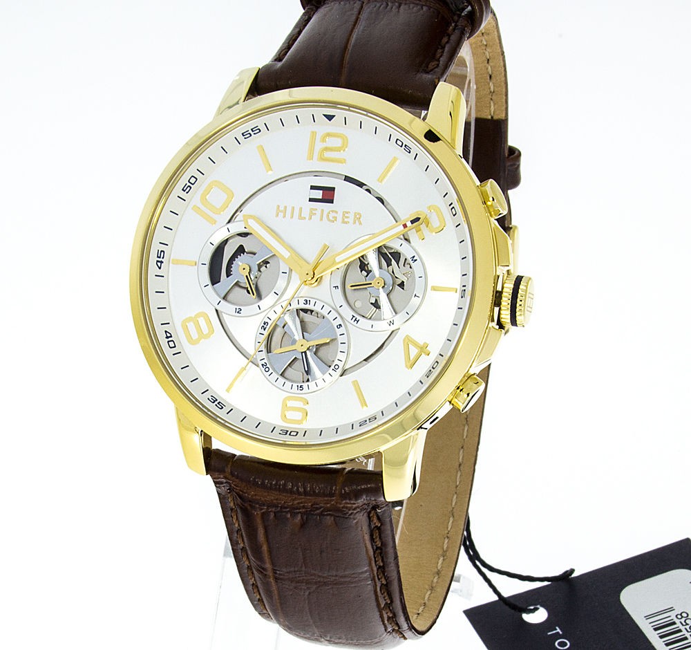 Men's Tommy Hilfiger Keagan watch features a 44mm silver dial with gold-tone accents, three subdials, and a brown leather strap with a textured finish.